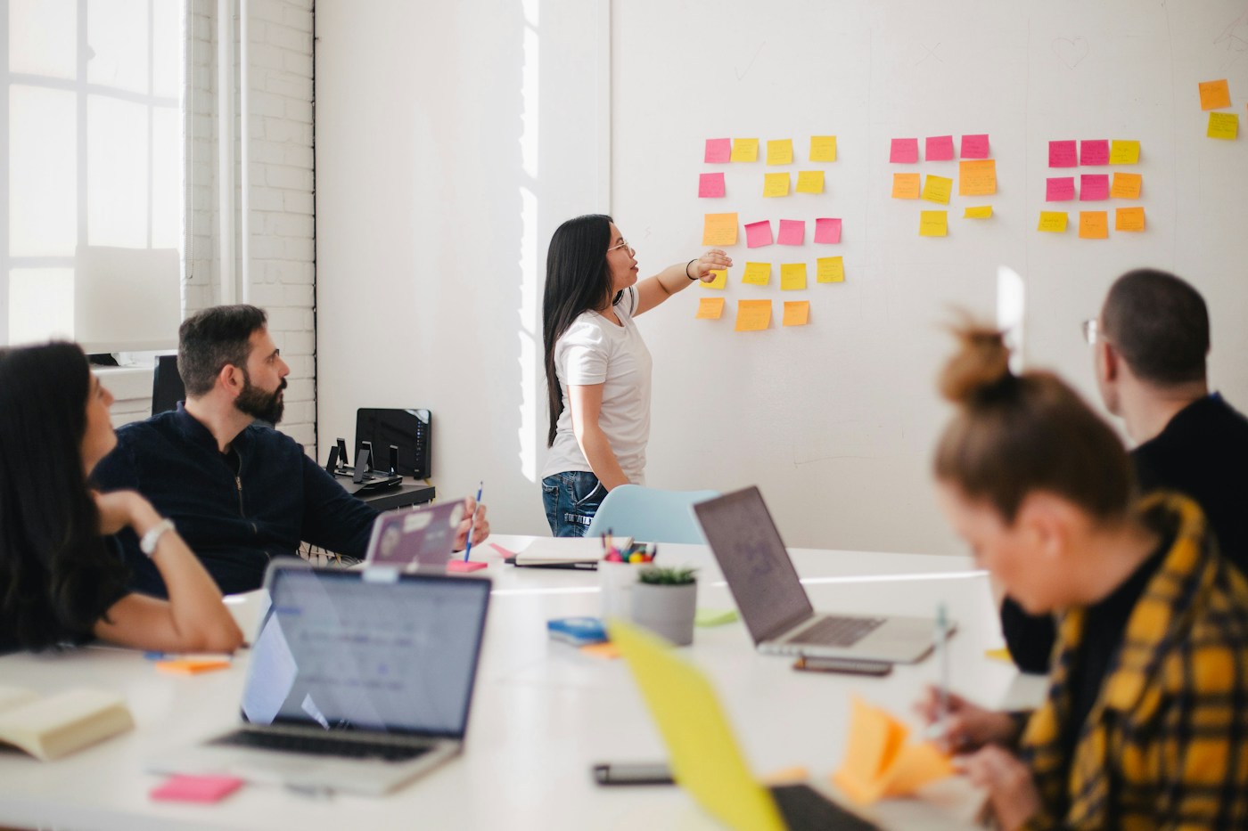 A team discussing ideas arranged on a wall of sticky notes