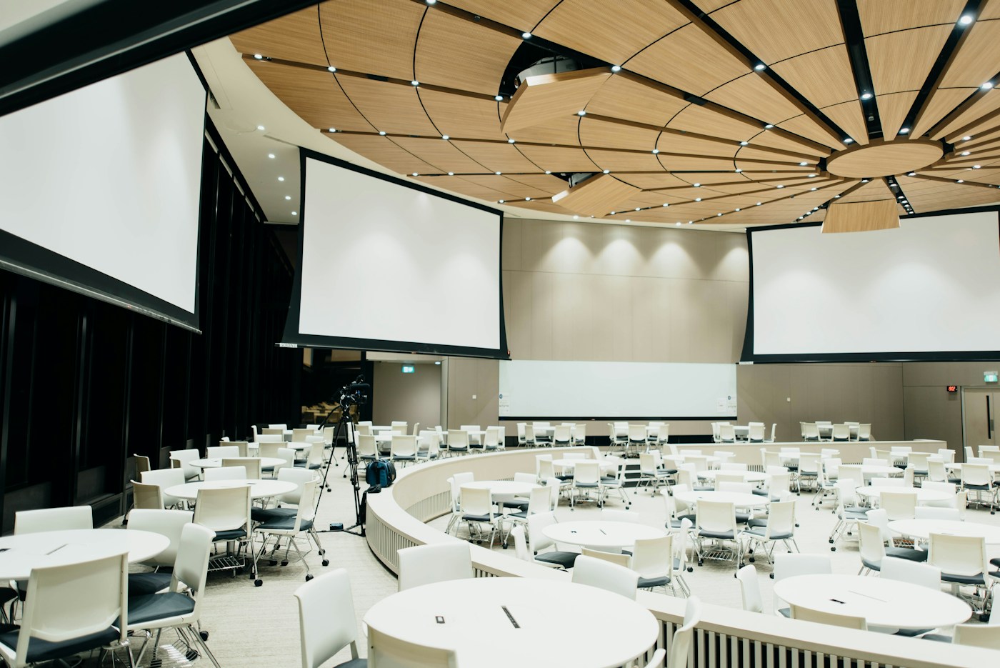 A business conference venue with presentation screens and delegate tables